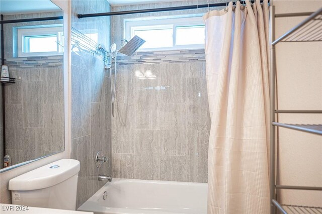 bathroom featuring shower / tub combo with curtain, toilet, and a wealth of natural light