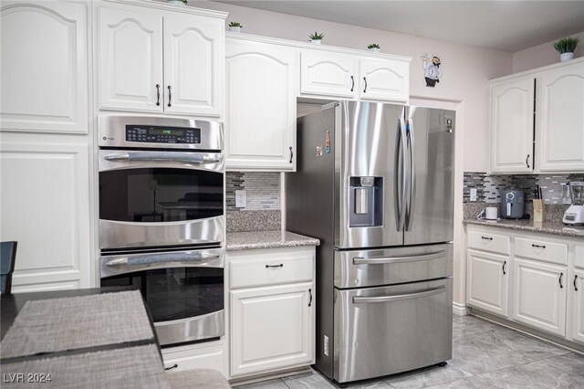 kitchen with white cabinetry, tasteful backsplash, stainless steel appliances, and light stone counters