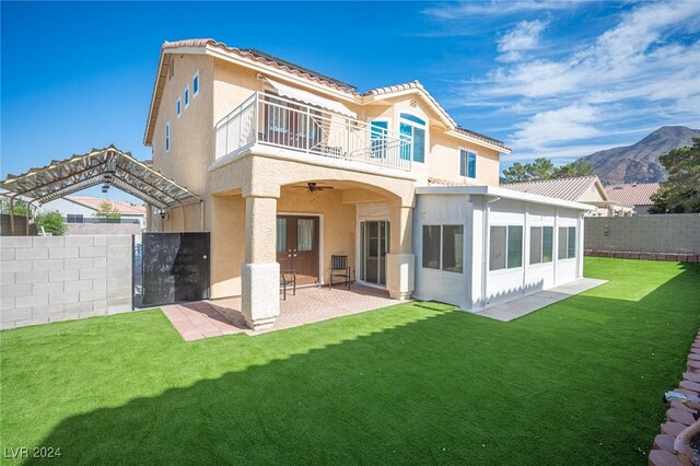 back of house with a patio area, a balcony, a lawn, a mountain view, and ceiling fan