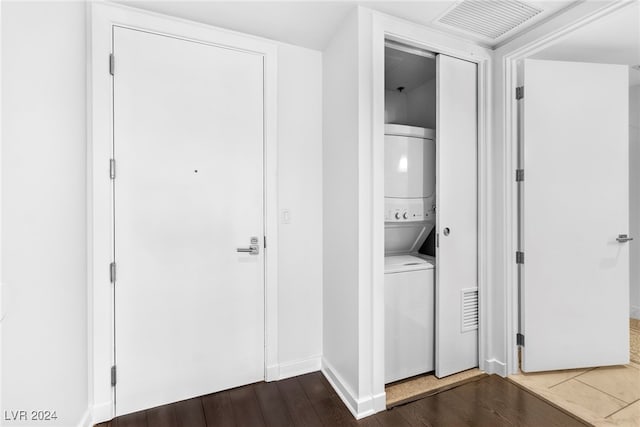 laundry area featuring stacked washer and clothes dryer and dark hardwood / wood-style floors