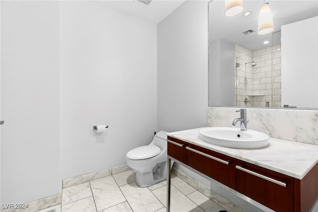 bathroom featuring a tile shower, vanity, and toilet