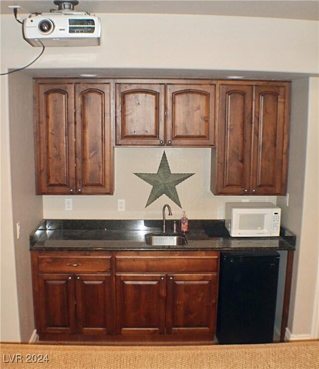 kitchen with dishwasher, dark stone counters, a sink, and white microwave