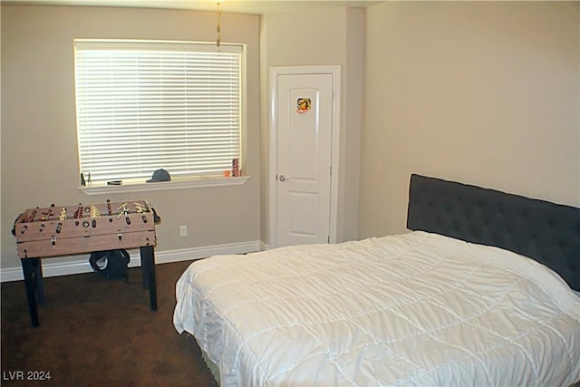 bedroom featuring baseboards, dark colored carpet, and multiple windows