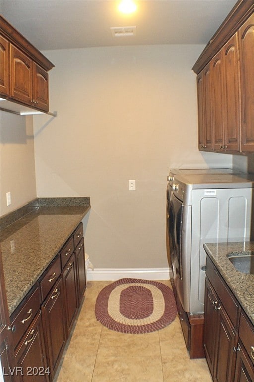 laundry area with light tile patterned flooring, cabinets, and independent washer and dryer