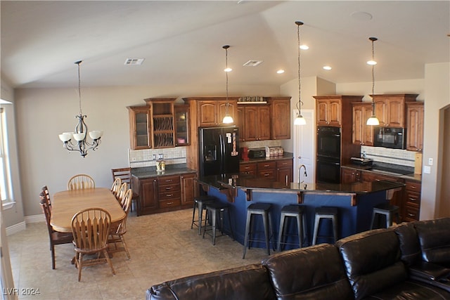 kitchen featuring light tile patterned flooring, black appliances, a kitchen bar, a large island with sink, and backsplash