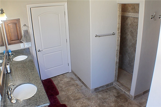 bathroom featuring tiled shower, dual vanity, and tile patterned floors