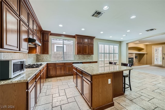 kitchen with backsplash, stainless steel appliances, a kitchen island, and a wealth of natural light