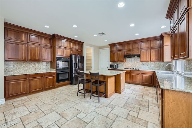 kitchen featuring decorative backsplash, stainless steel appliances, a kitchen island, and sink