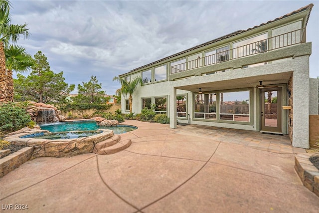 view of swimming pool featuring pool water feature, ceiling fan, a patio area, and an in ground hot tub