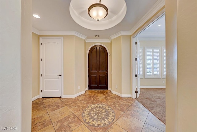 foyer entrance featuring arched walkways, visible vents, ornamental molding, light tile patterned flooring, and baseboards