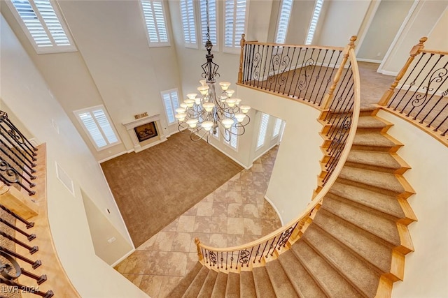 stairs with a towering ceiling, plenty of natural light, and a notable chandelier