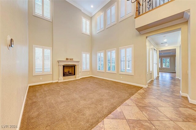 unfurnished living room featuring a wealth of natural light, a high end fireplace, light tile patterned floors, and ornamental molding