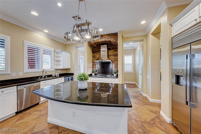 kitchen with wall chimney range hood, a kitchen island, appliances with stainless steel finishes, and white cabinets