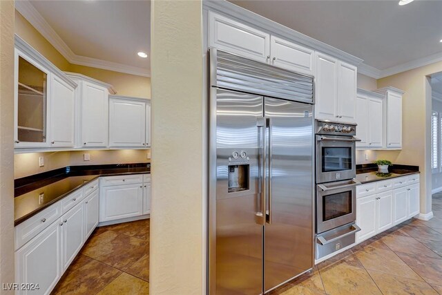 kitchen featuring light tile patterned flooring, ornamental molding, appliances with stainless steel finishes, and white cabinets