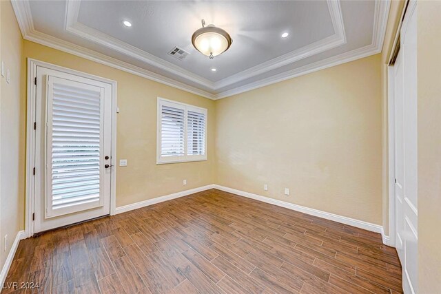 unfurnished room featuring ornamental molding, wood-type flooring, and a raised ceiling