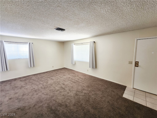 empty room with light carpet and a textured ceiling