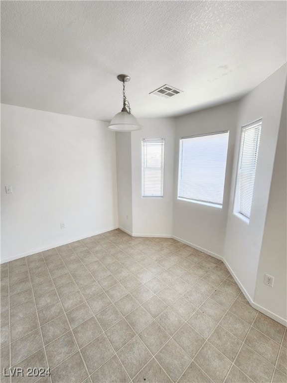 spare room with a textured ceiling and light tile patterned floors