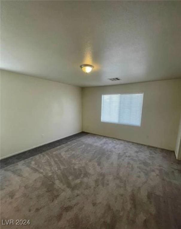 spare room with dark colored carpet