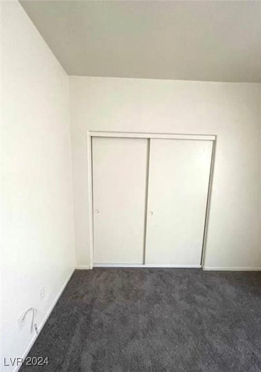 unfurnished bedroom featuring dark carpet and a closet