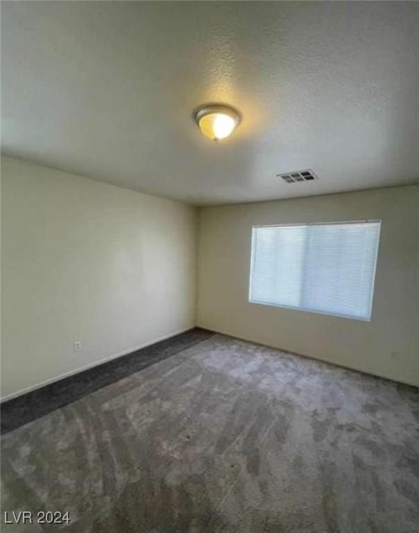 unfurnished room featuring dark carpet and a textured ceiling