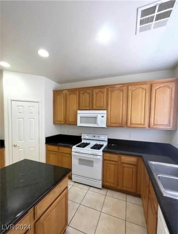 kitchen featuring sink, light tile patterned floors, and white appliances