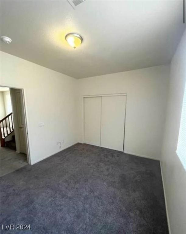 unfurnished bedroom with a closet and dark colored carpet