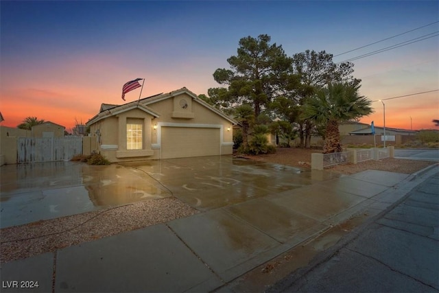 view of front facade with concrete driveway, an attached garage, fence, and stucco siding