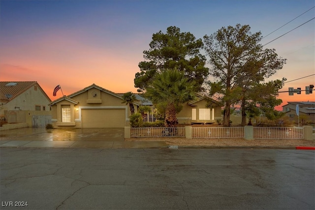 view of front of house with a fenced front yard, concrete driveway, an attached garage, and stucco siding