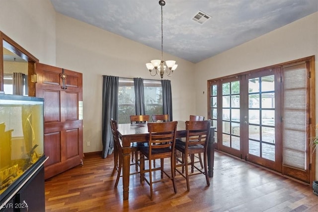 dining area featuring visible vents, wood finished floors, vaulted ceiling, french doors, and a chandelier