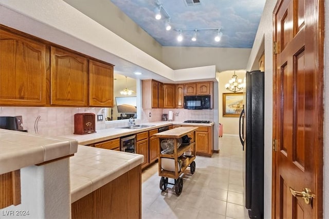 kitchen featuring brown cabinets, a sink, tile countertops, and black appliances