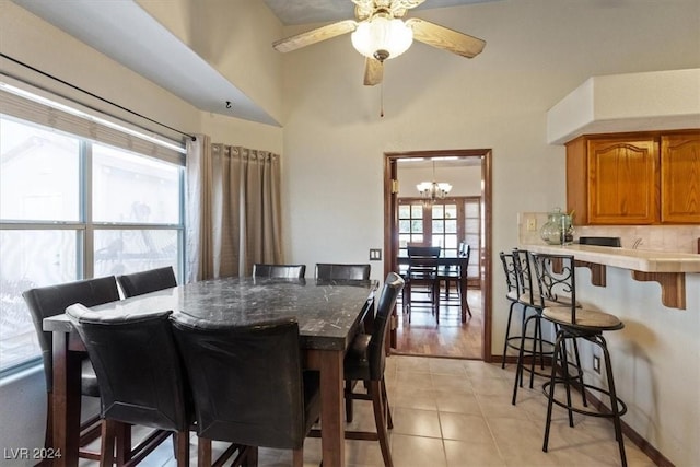 dining area with light tile patterned floors, ceiling fan with notable chandelier, and baseboards