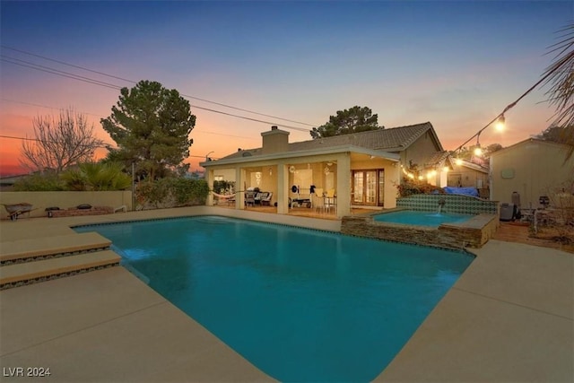 outdoor pool featuring an in ground hot tub, a patio area, and a fenced backyard