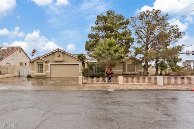 view of front of property with a fenced front yard, driveway, a garage, and stucco siding