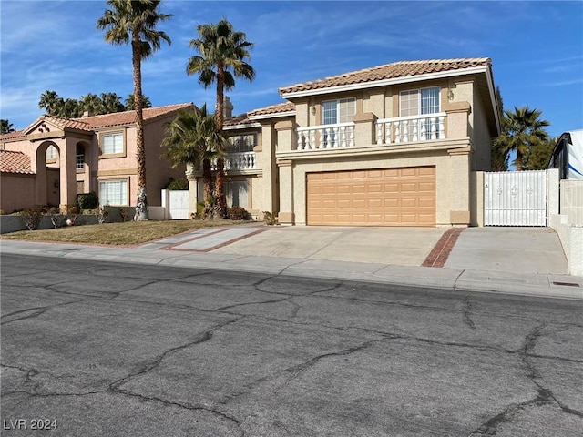 mediterranean / spanish home with stucco siding, an attached garage, driveway, a tile roof, and a balcony