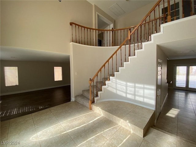 stairway featuring baseboards, tile patterned flooring, and a high ceiling