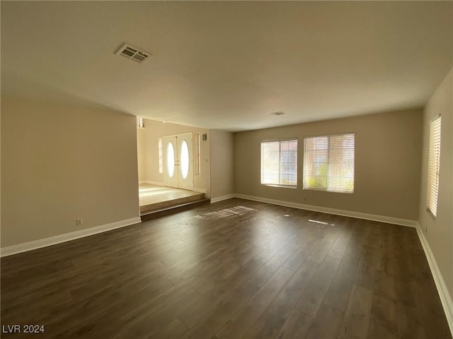 empty room featuring dark wood finished floors, baseboards, french doors, and visible vents