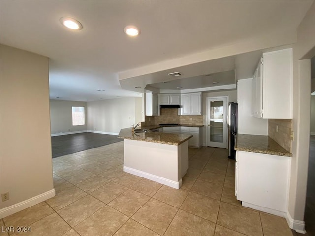 kitchen featuring a sink, open floor plan, dark stone countertops, white cabinets, and a peninsula