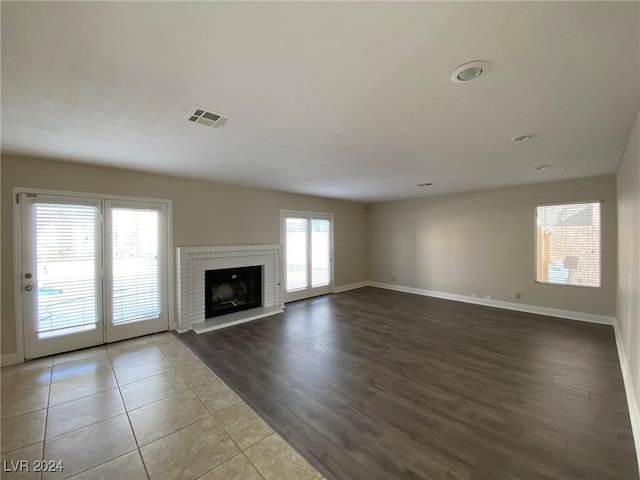 unfurnished living room with baseboards, wood finished floors, visible vents, and a fireplace