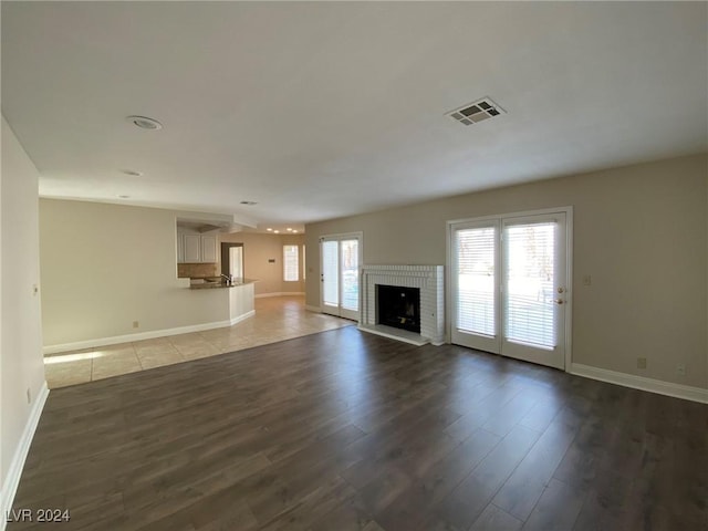 unfurnished living room featuring plenty of natural light, dark wood-style flooring, and visible vents