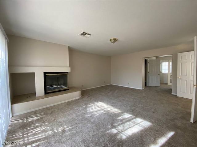 unfurnished living room with baseboards, a glass covered fireplace, visible vents, and carpet floors