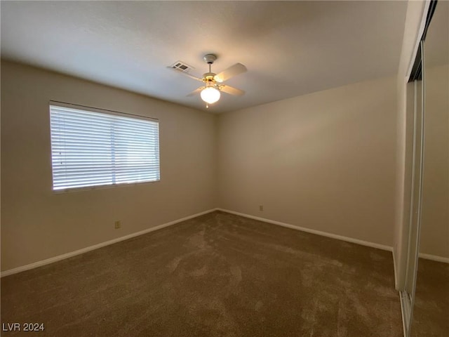 unfurnished room with baseboards, visible vents, ceiling fan, and dark colored carpet