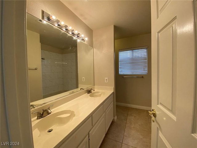 full bathroom with a sink, baseboards, double vanity, and tile patterned floors