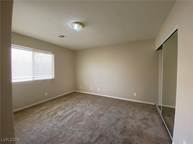 carpeted empty room featuring baseboards and visible vents