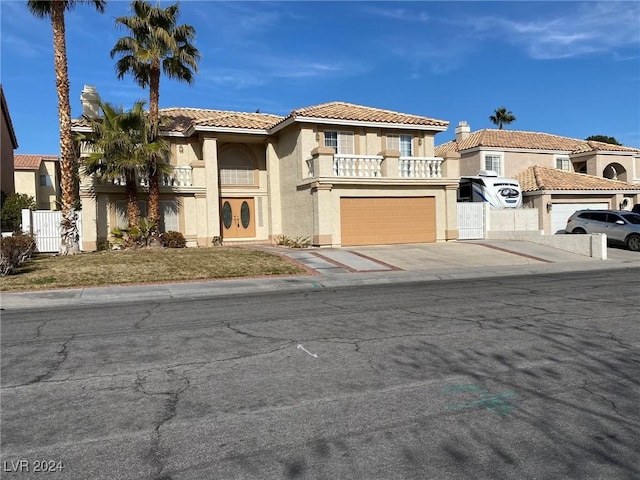 mediterranean / spanish-style home featuring stucco siding, a garage, concrete driveway, a tile roof, and a balcony