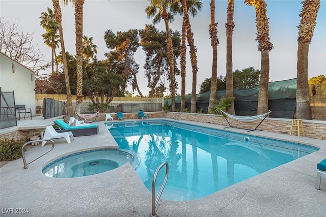 view of swimming pool featuring a fenced backyard and a pool with connected hot tub