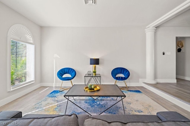 living area featuring decorative columns, visible vents, baseboards, and wood finished floors