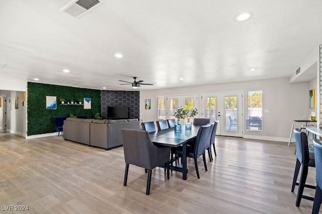 dining room with an accent wall, visible vents, baseboards, french doors, and light wood finished floors