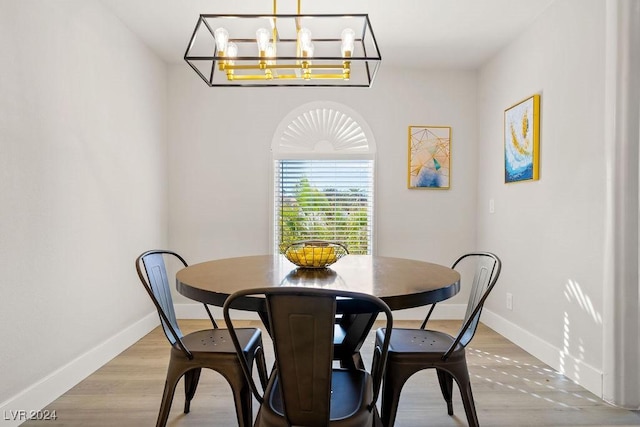 dining space featuring an inviting chandelier, baseboards, and wood finished floors