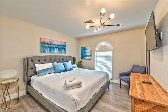 bedroom with light wood-type flooring, visible vents, baseboards, and an inviting chandelier