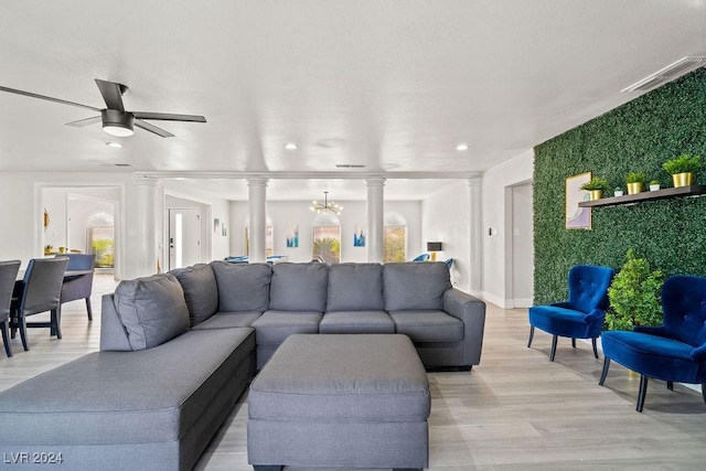 living area with visible vents, a healthy amount of sunlight, light wood-style flooring, and ornate columns